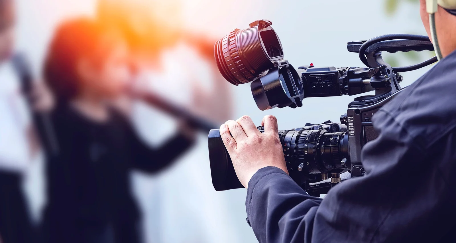 A camera operator filming a closeup of an actor's hands holding a prop on a small set with minimal crew