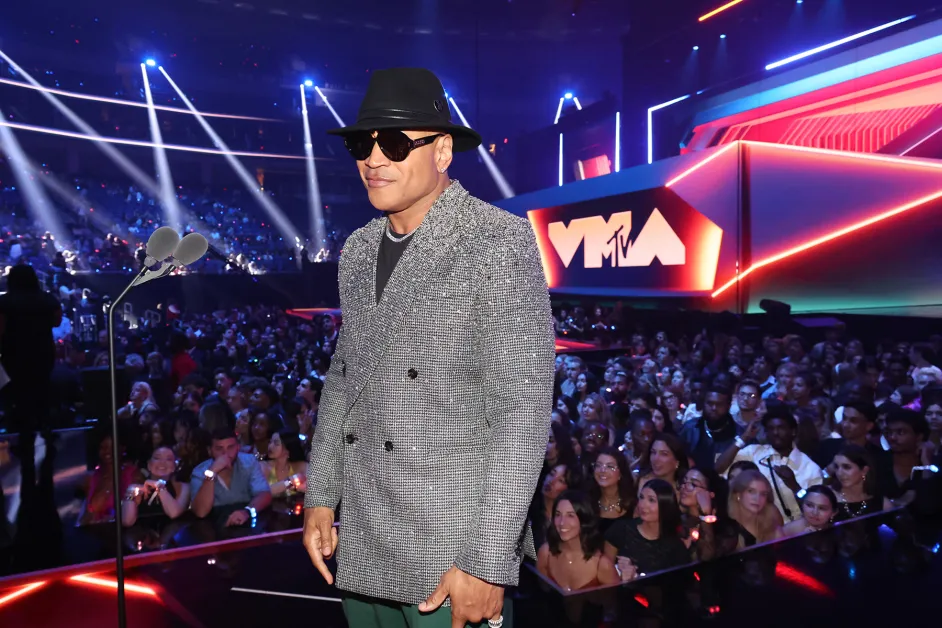 A candid audience reaction shot at the VMAs, with a celebrity in the crowd turning toward the stage with a surprised expression as lights wash over the audience