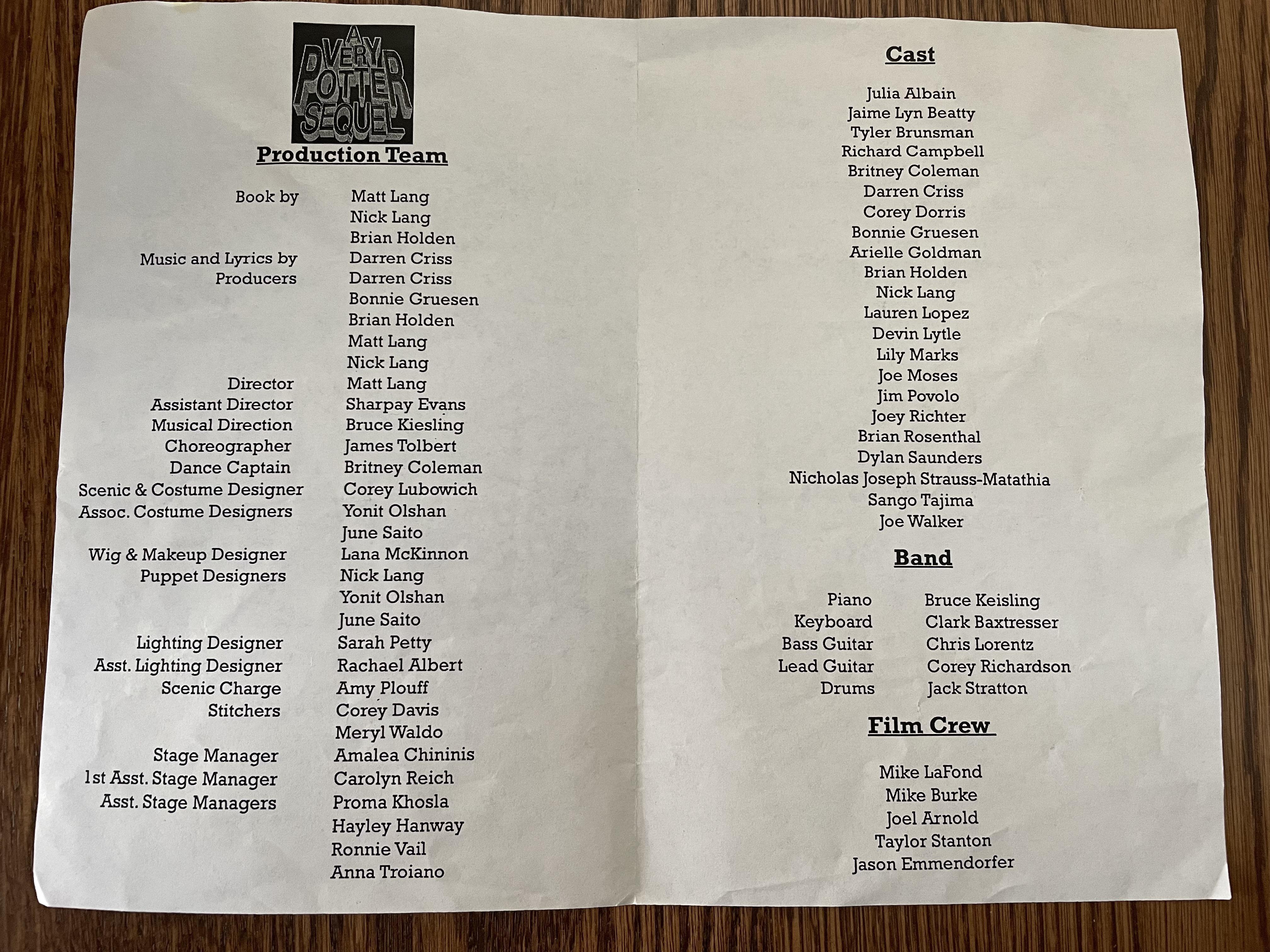 A close-up view of an open theater program showing a cast list page under soft auditorium lighting