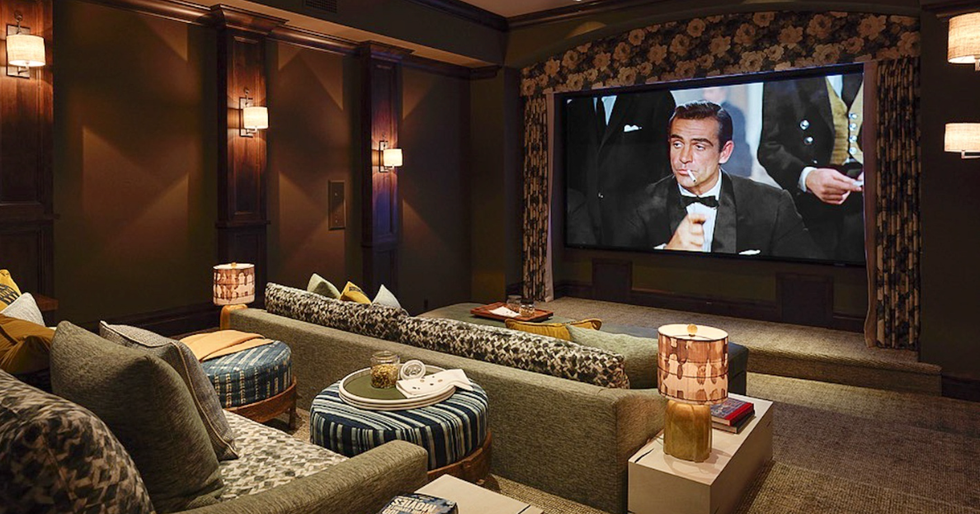 A cozy living room at night with a television showing a movie scene, a coffee table with snacks, and dim lamp lighting