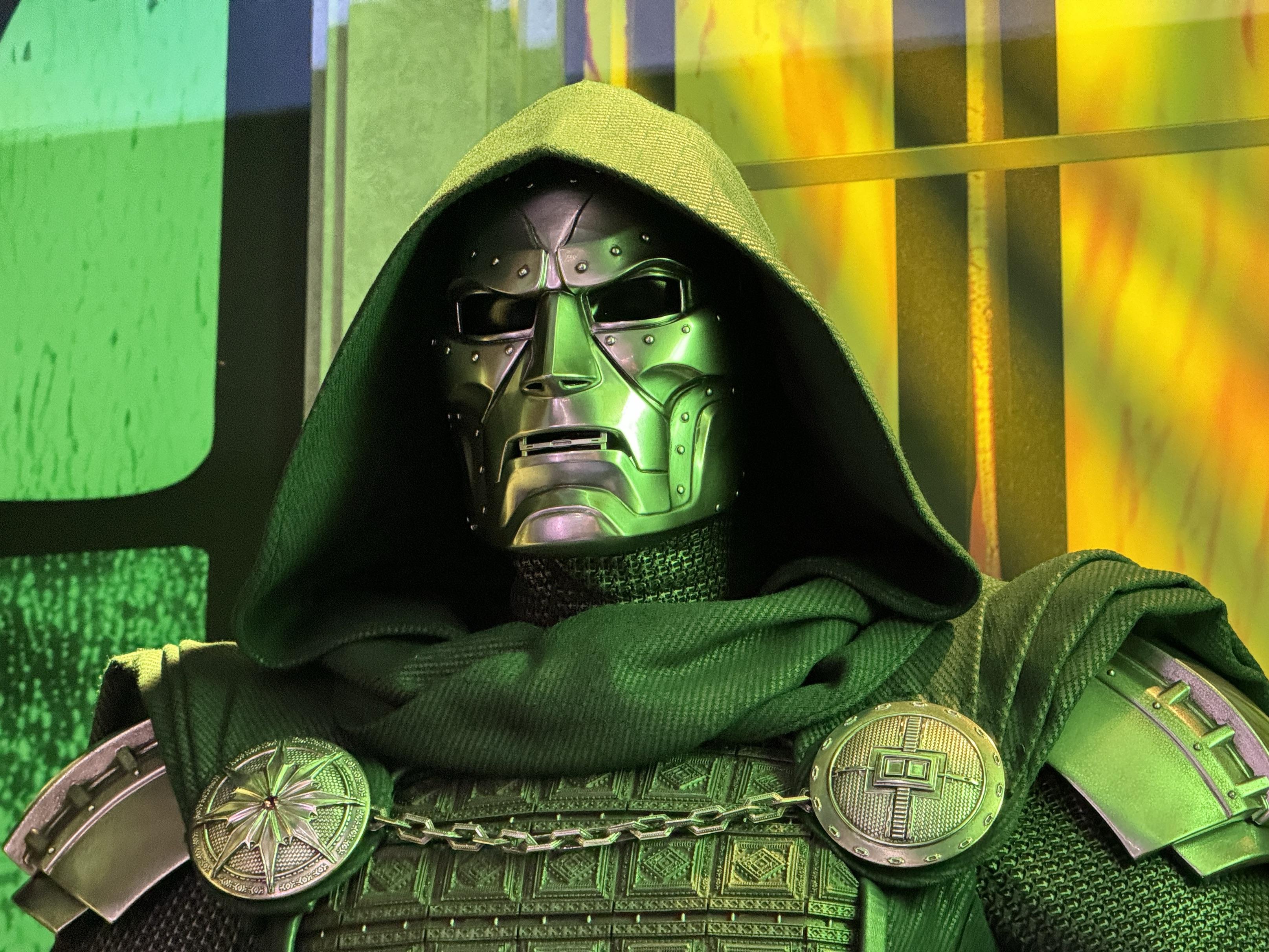 A fan in Doctor Doom cosplay wearing a green hooded cloak and metal mask at a convention