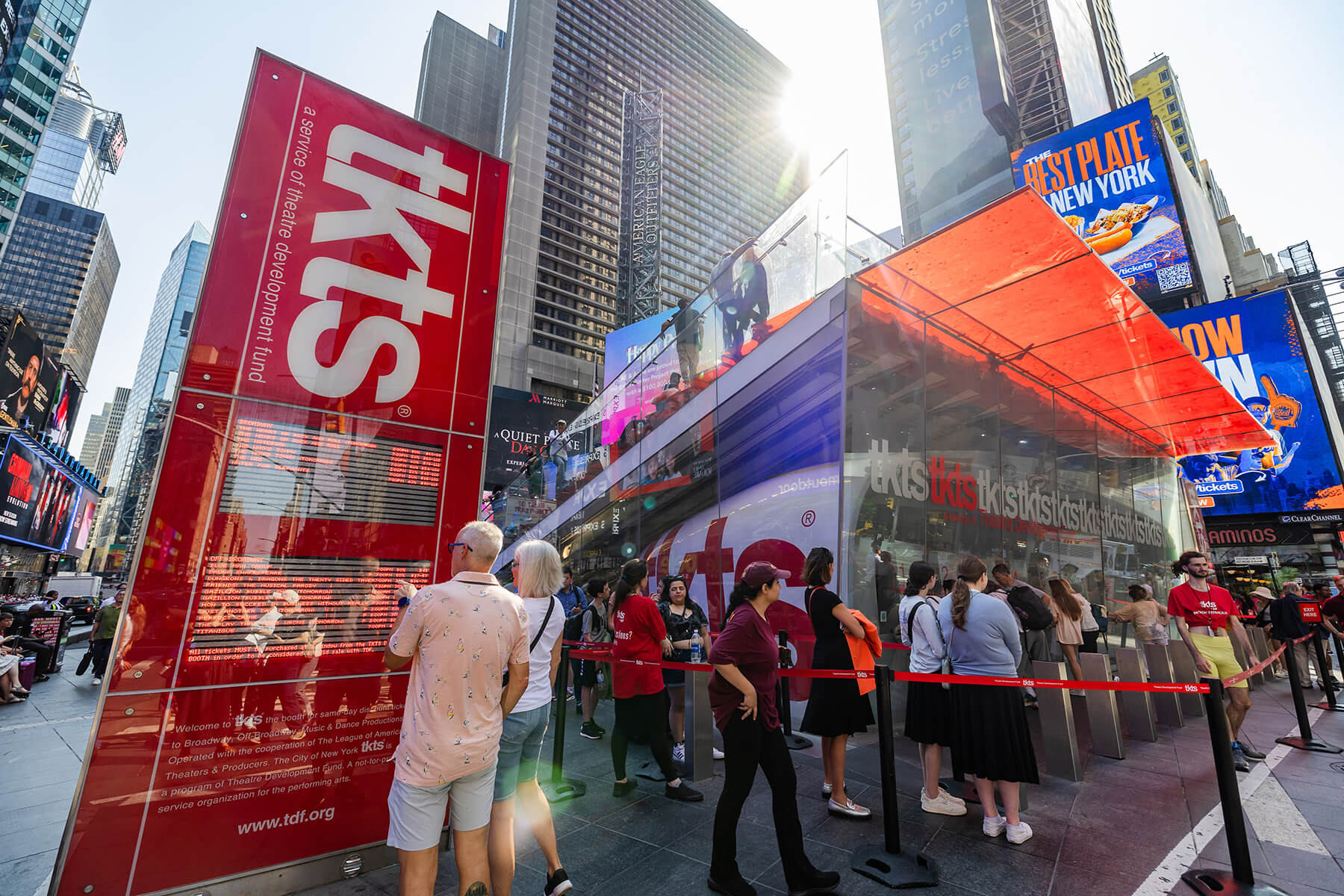 A line of theatergoers outside a Broadway theater box office near Times Square in New York City, people bundled in jackets and holding coffee