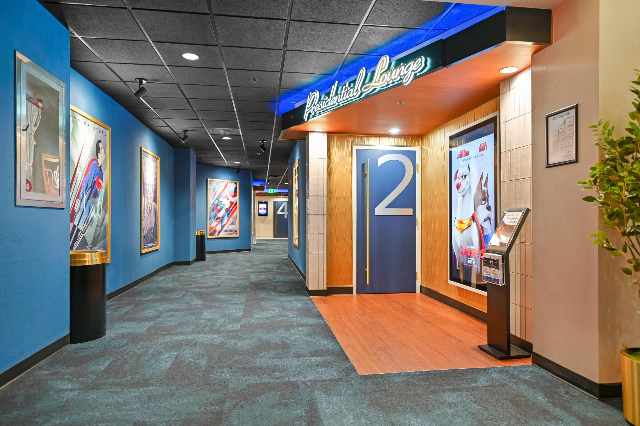 A modern multiplex theater lobby with a popcorn counter, digital showtime boards, and moviegoers walking toward the auditoriums