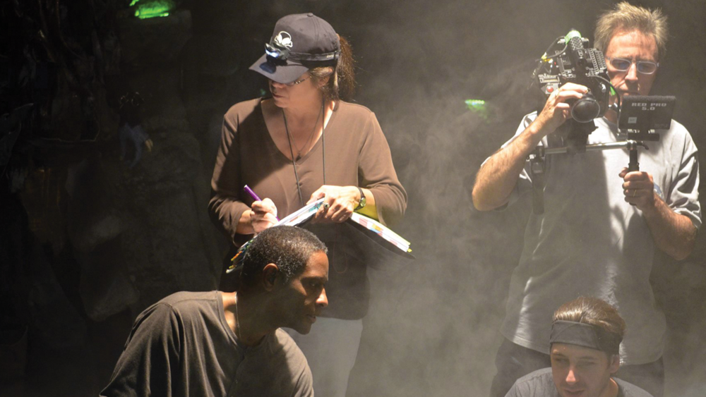 A script supervisor holding a clipboard with continuity notes while watching actors reset for another take on a film set