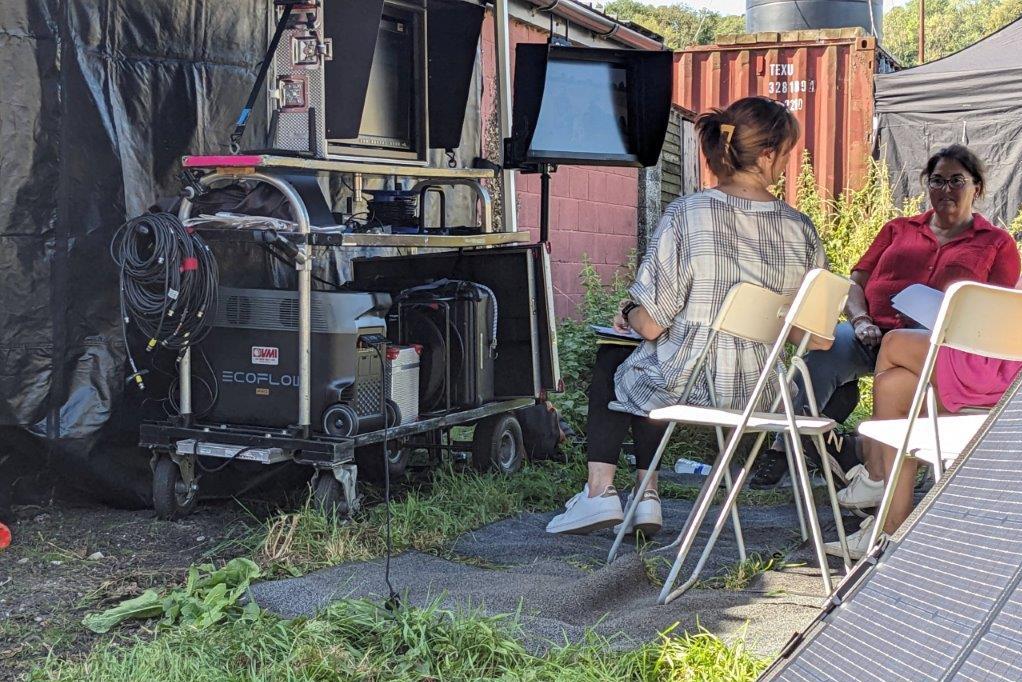 A video village area with monitors and folding chairs as crew members watch playback on a commercial set, candid photograph