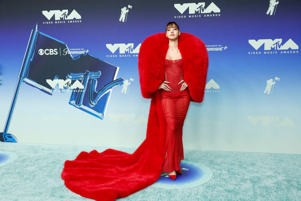 A wide shot of the red carpet outside the MTV Video Music Awards venue, with photographers lining barricades and artists posing under bright step-and-repeat lighting