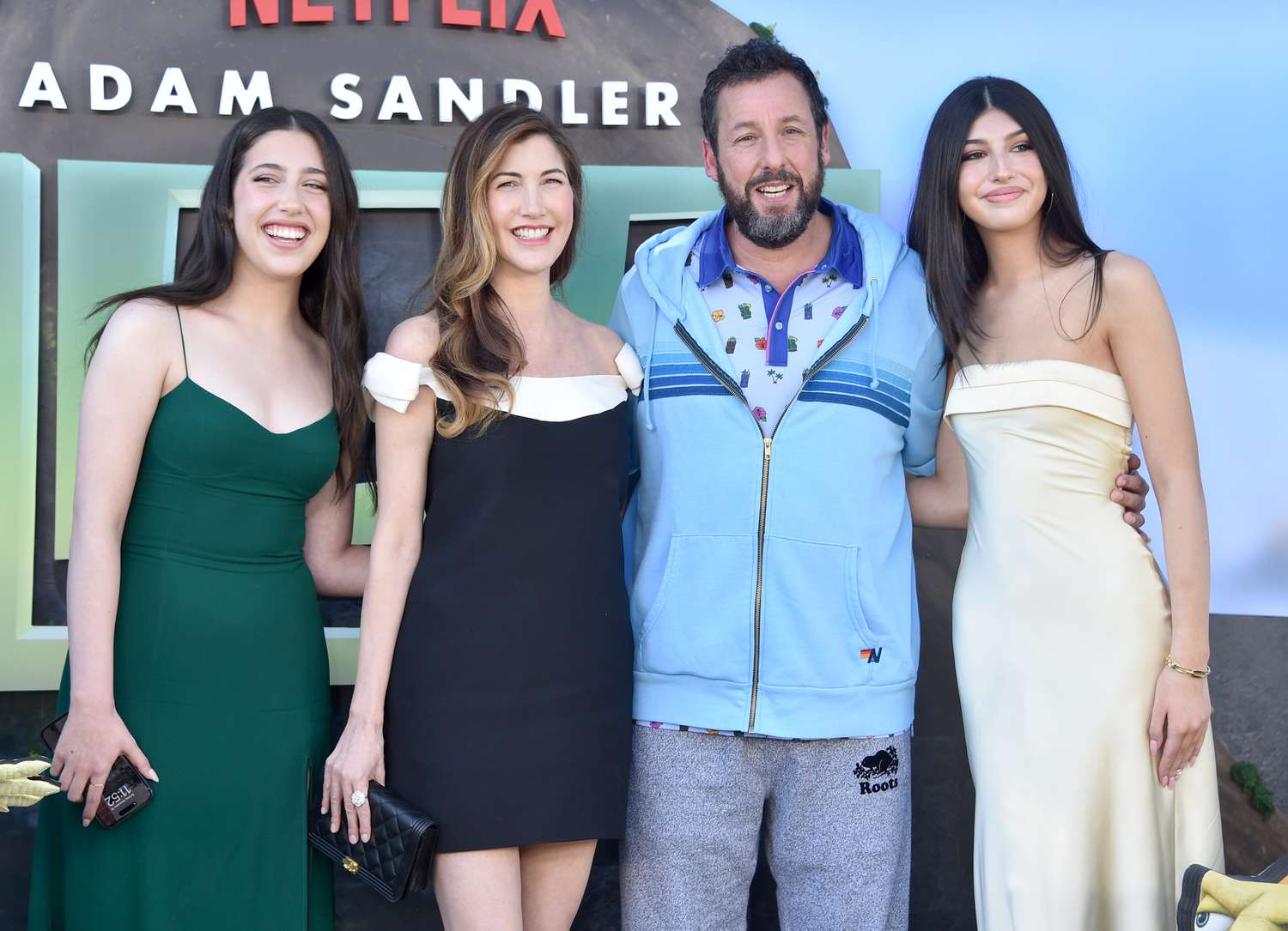 Adam Sandler posing at an event, smiling toward photographers.