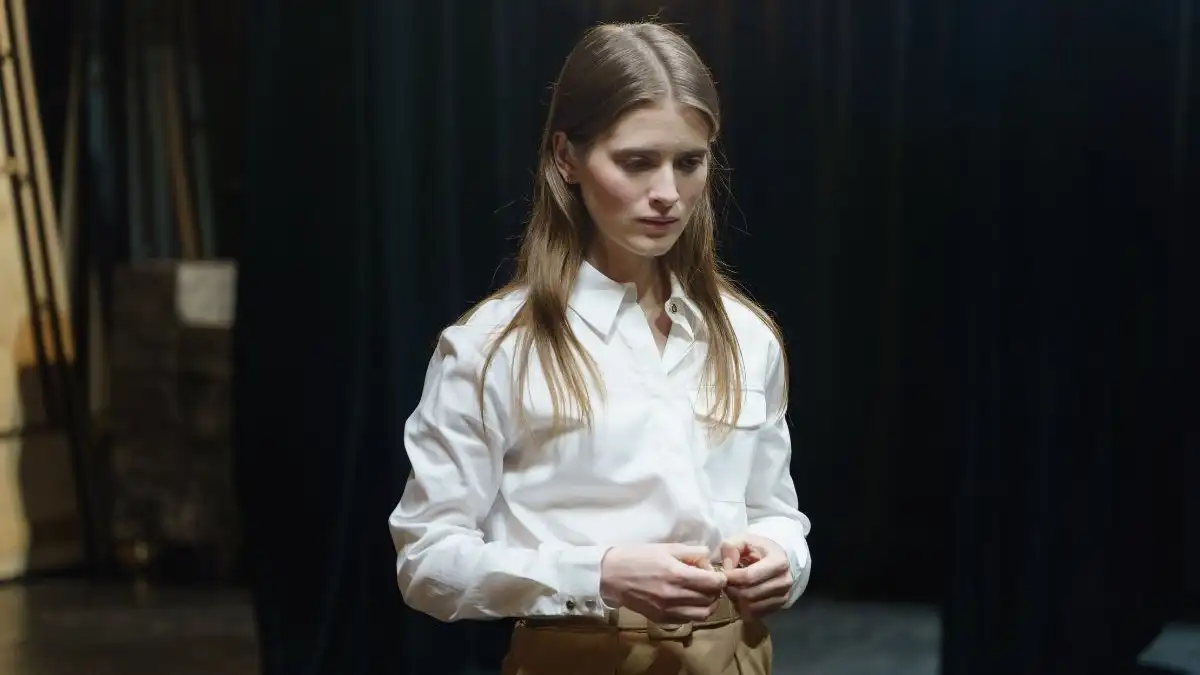 An actor standing on a simple set in front of a cinema camera and a soft key light, holding a script page while a casting team watches from a monitor