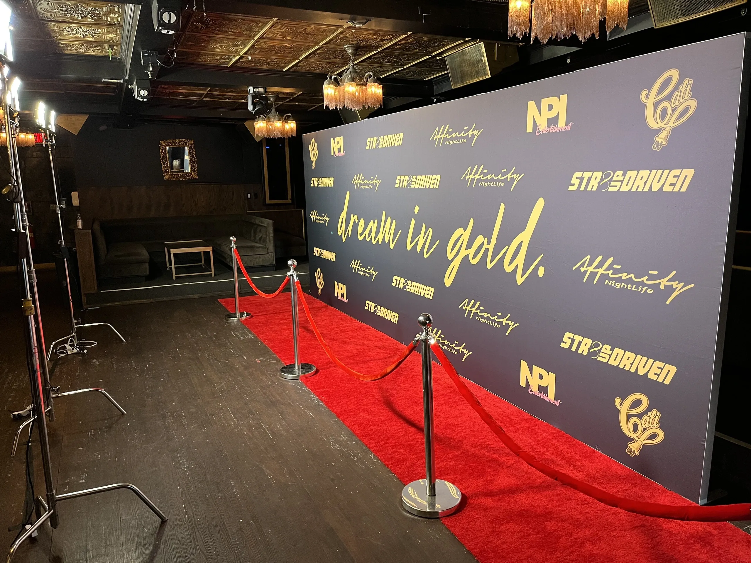 Attendees posing on a red carpet in front of a step-and-repeat wall outside a theater at night