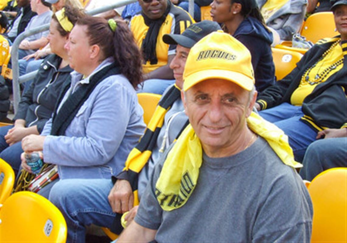 Background actors seated in stadium-style rows while an assistant director points toward seating sections during setup