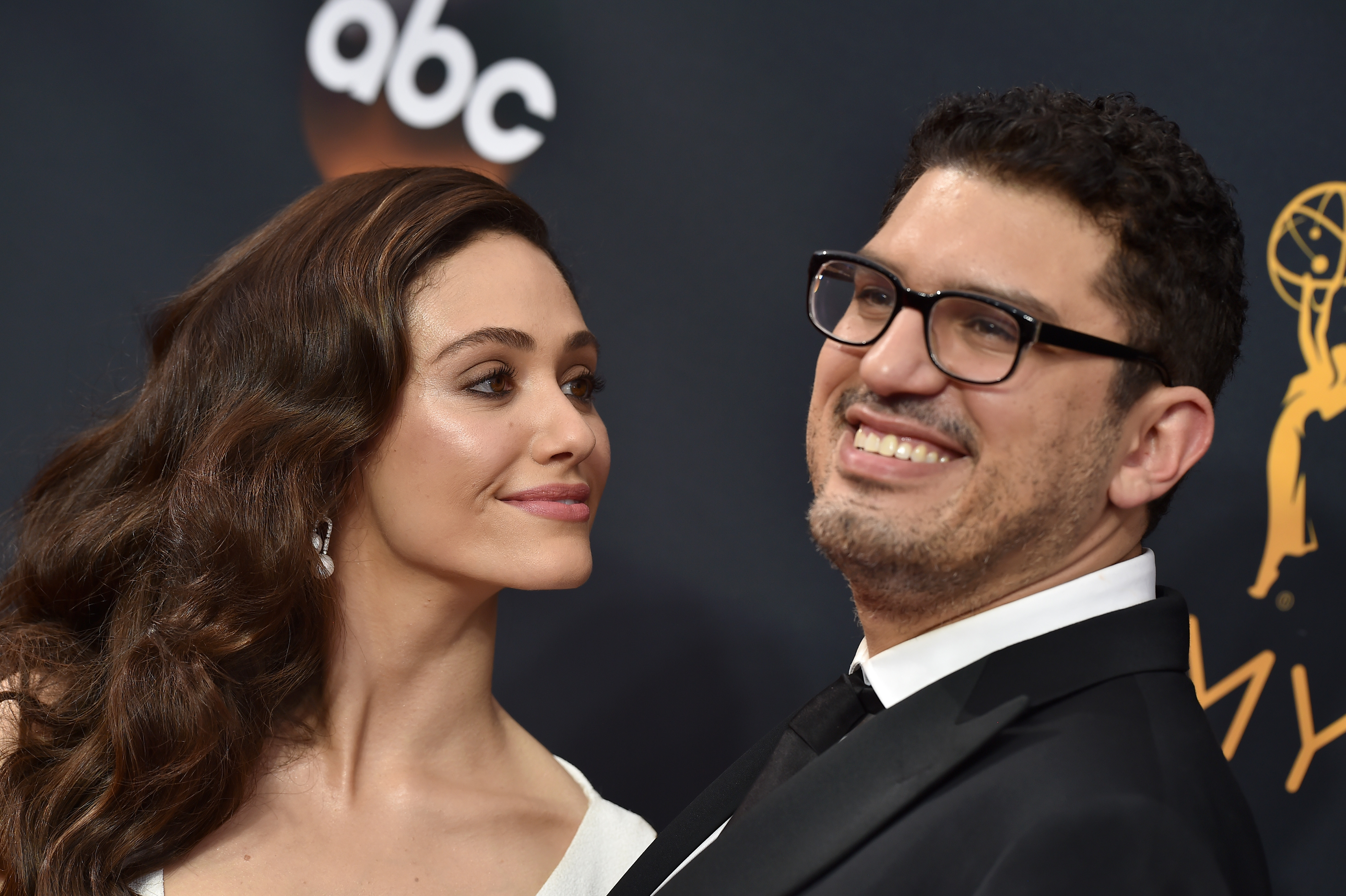Emmy Rossum and Sam Esmail attending an event together, standing close and smiling for photographers