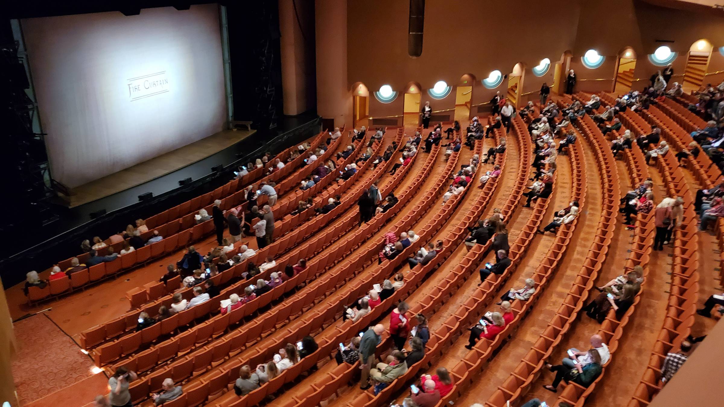 Orchestra-level seats in a theater with a clear center aisle facing a proscenium stage