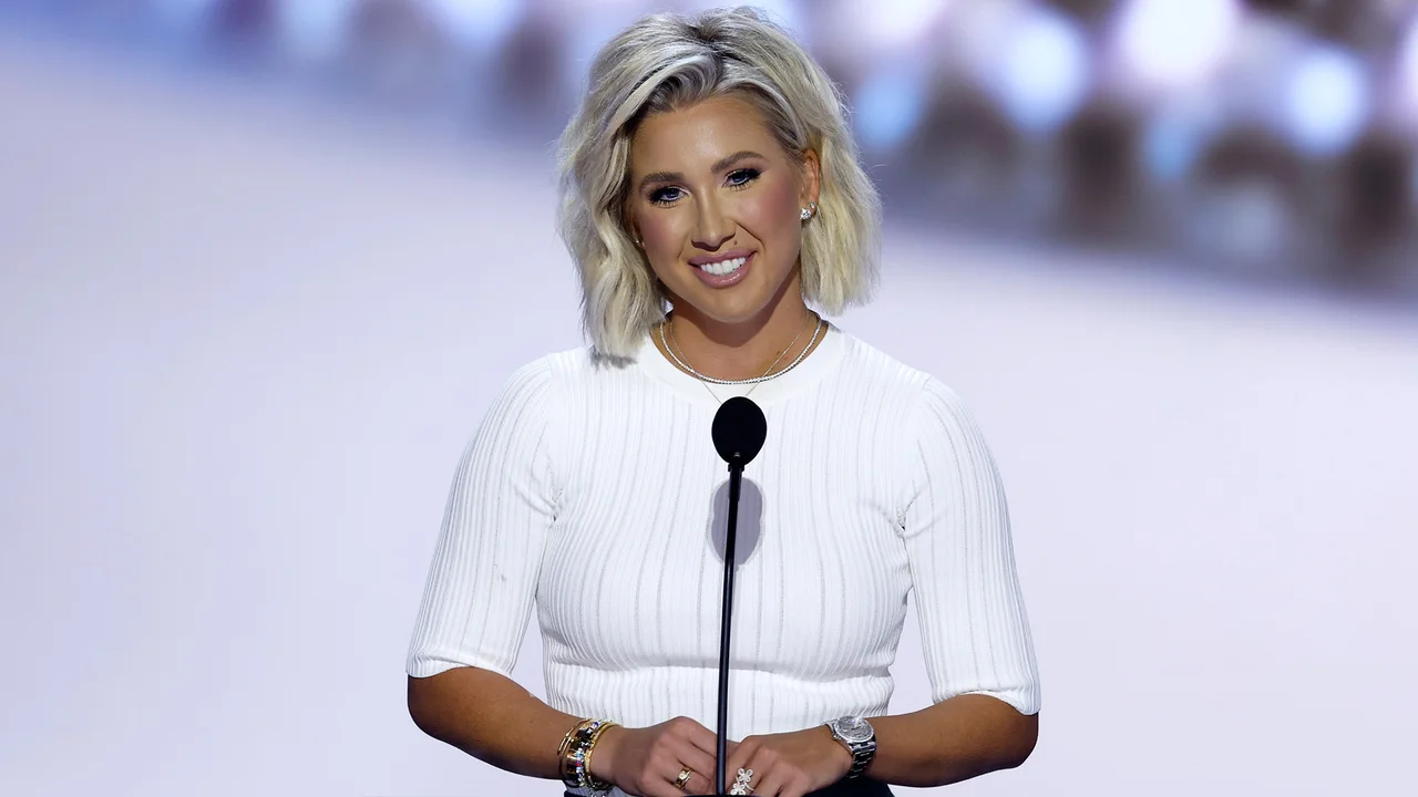 Savannah Chrisley holding a sonogram and cradling her baby bump while standing next to Jason