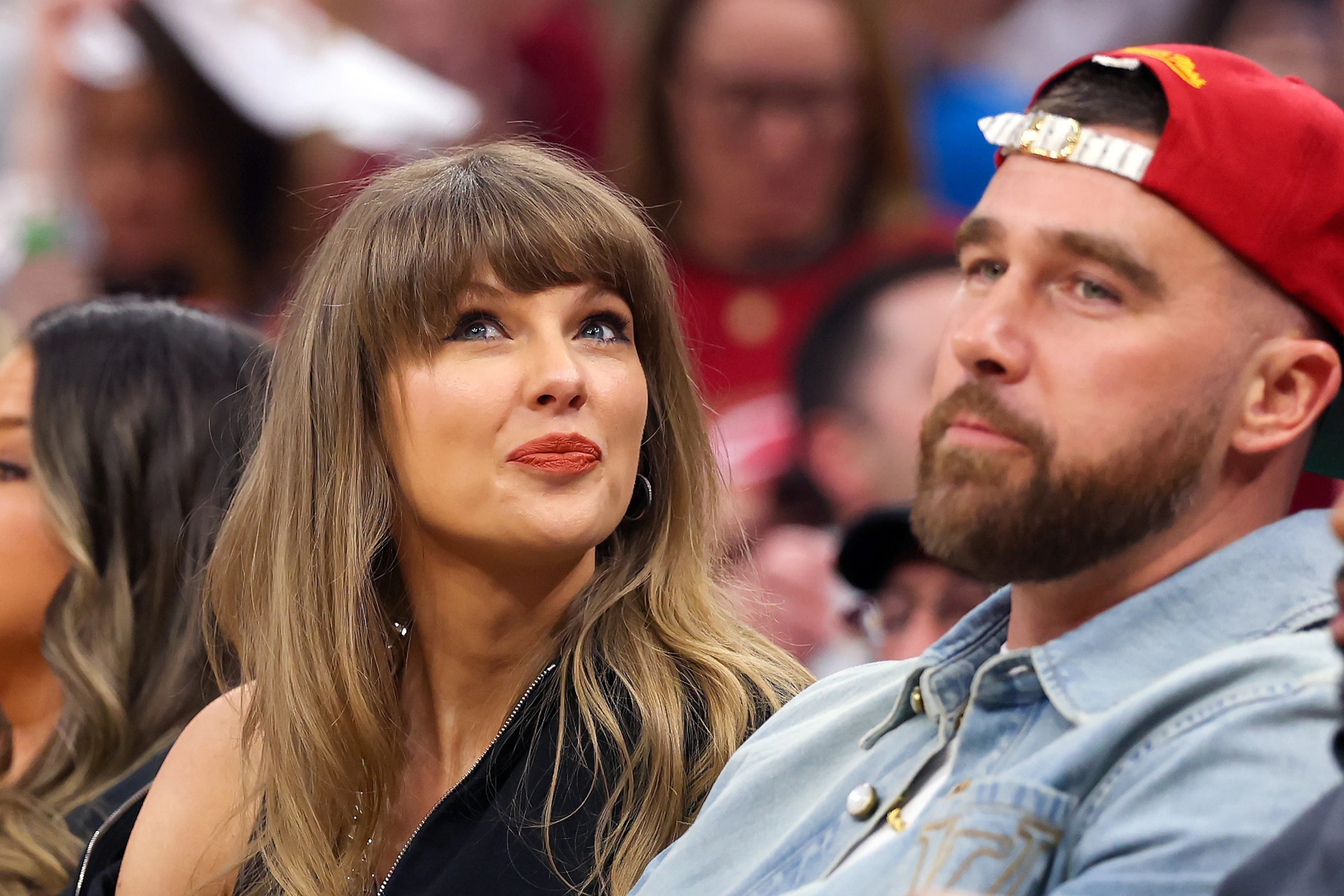 Taylor Swift and Travis Kelce at a public event, photographed together with fans and cameras nearby.
